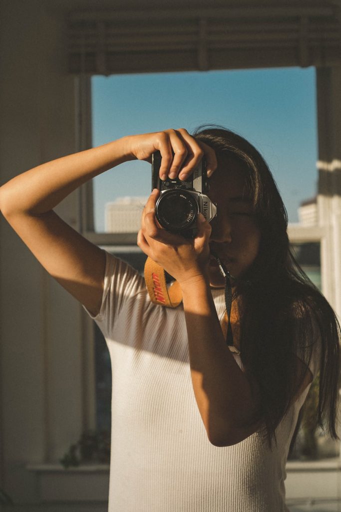 Image of an Asian female holding a Nikon camera. Vintage aesthetic