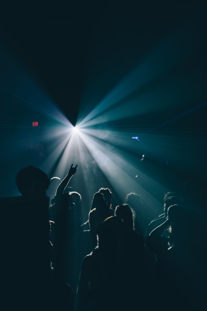 Image of rave with a strobe light. Lots of people dancing to techno, indie, pop, rock, rap music