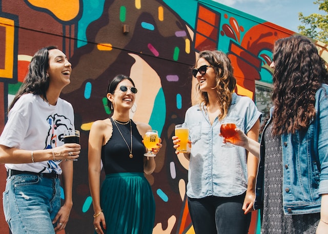 Female friends enjoying a beverage in the sun behind graffiti