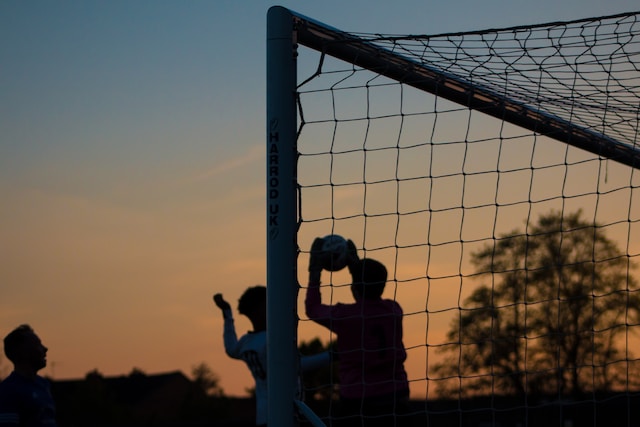 A picture of kids playing football with netted goals at sunset