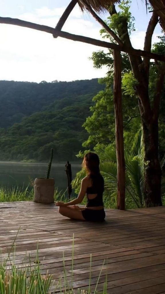 A woman doing yoga in a wooden house facing the lake