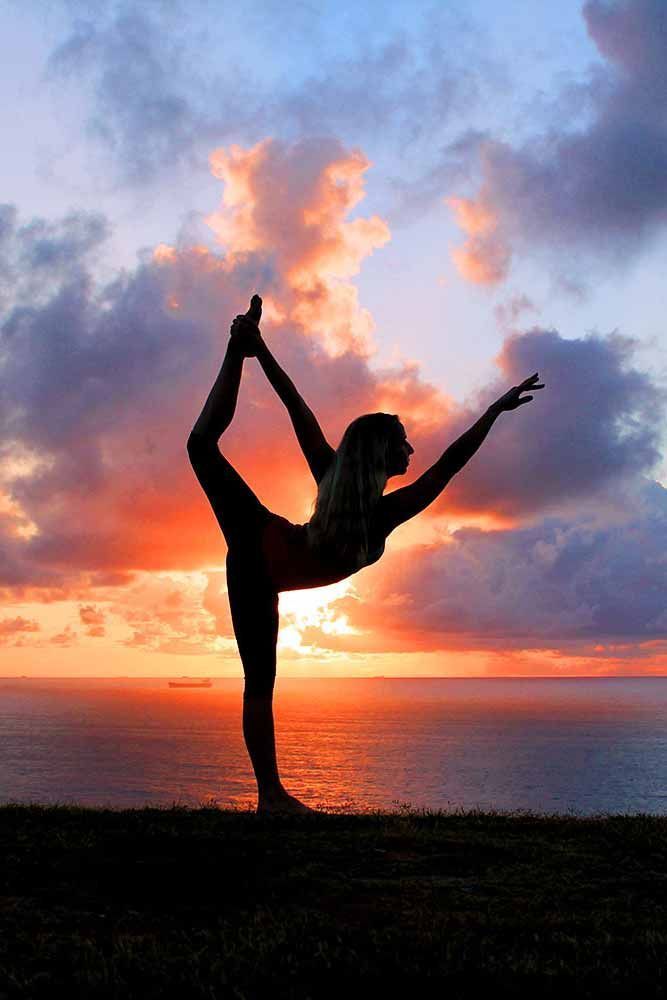 A woman doing yoga by the sea at sunset